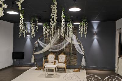 Salle spacieuse avec carrelage au sol, murs clairs, plafond noir, tables et chaises dispersées.