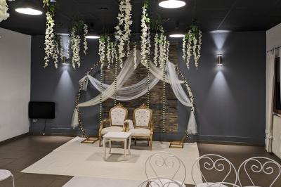 Salle spacieuse avec carrelage au sol, murs clairs, plafond noir, tables et chaises dispersées.