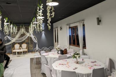 Salle spacieuse avec carrelage au sol, murs clairs, plafond noir, tables et chaises dispersées.