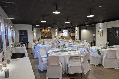 Salle spacieuse avec carrelage au sol, murs clairs, plafond noir, tables et chaises dispersées.