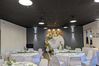 Salle spacieuse avec carrelage au sol, murs clairs, plafond noir, tables et chaises dispersées.