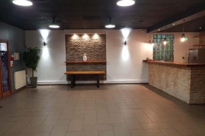 Salle spacieuse avec carrelage au sol, murs clairs, plafond noir, tables et chaises dispersées.