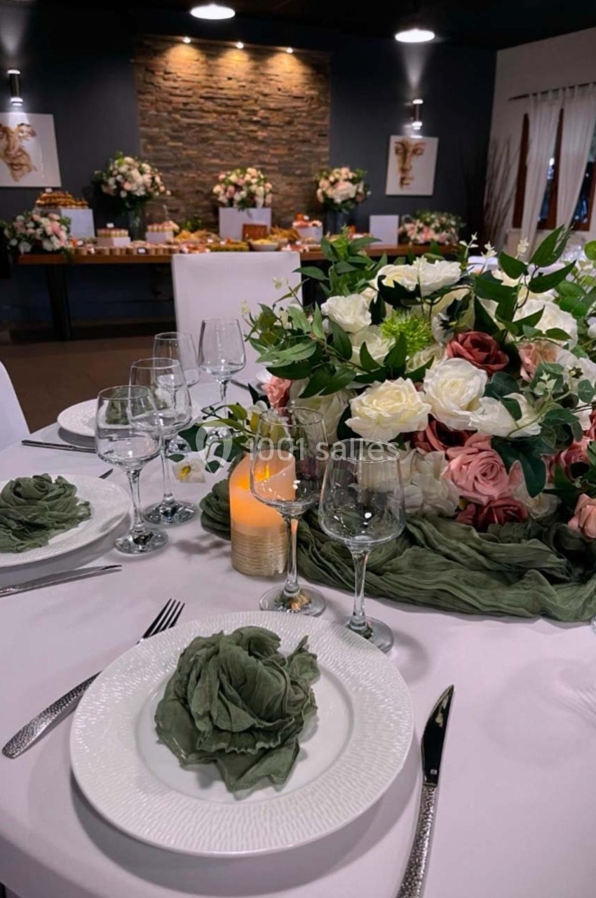 Table élégamment dressée avec des assiettes blanches, serviettes pliées, verres, bougie et centre de table floral.