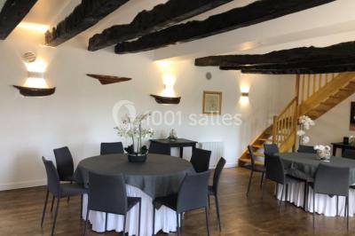 Salle de réception éclairée par des lumières violettes, avec tables hautes décorées de bougies et un espace central dégagé.