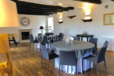Salle de réception éclairée par des lumières violettes, avec tables hautes décorées de bougies et un espace central dégagé.