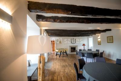 Salle de réception éclairée par des lumières violettes, avec tables hautes décorées de bougies et un espace central dégagé.