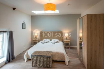 Salle de réception éclairée par des lumières violettes, avec tables hautes décorées de bougies et un espace central dégagé.