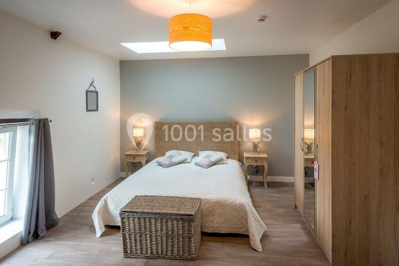 Chambre lumineuse avec lit double, mobilier en bois clair, panier en osier et lampe suspendue.