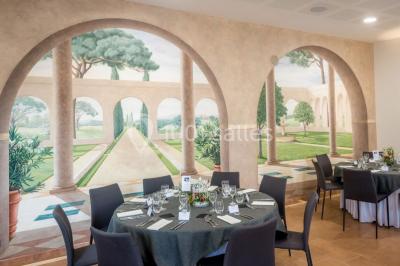Salle de réception éclairée par des lumières violettes, avec tables hautes décorées de bougies et un espace central dégagé.