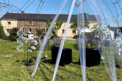 Salle de réception éclairée par des lumières violettes, avec tables hautes décorées de bougies et un espace central dégagé.