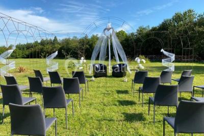 Salle de réception éclairée par des lumières violettes, avec tables hautes décorées de bougies et un espace central dégagé.