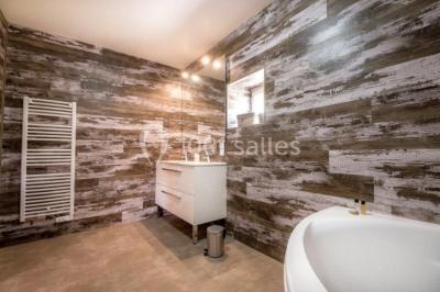 Salle de réception éclairée par des lumières violettes, avec tables hautes décorées de bougies et un espace central dégagé.