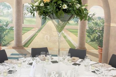 Salle de réception éclairée par des lumières violettes, avec tables hautes décorées de bougies et un espace central dégagé.