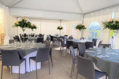 Salle de réception éclairée par des lumières violettes, avec tables hautes décorées de bougies et un espace central dégagé.