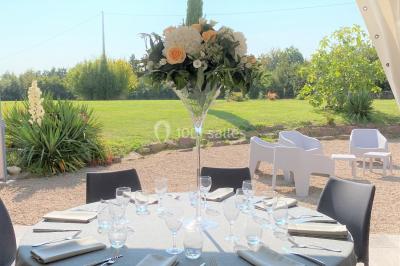 Salle de réception éclairée par des lumières violettes, avec tables hautes décorées de bougies et un espace central dégagé.
