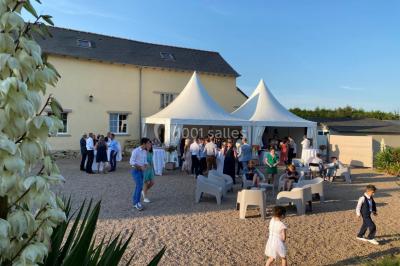 Salle de réception éclairée par des lumières violettes, avec tables hautes décorées de bougies et un espace central dégagé.