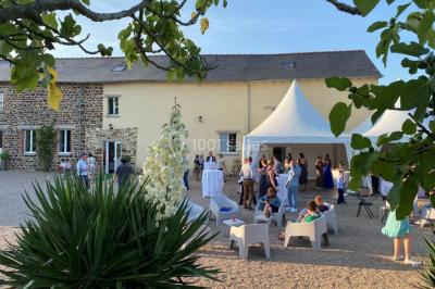 Salle de réception éclairée par des lumières violettes, avec tables hautes décorées de bougies et un espace central dégagé.
