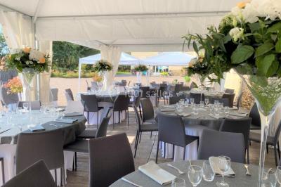 Salle de réception éclairée par des lumières violettes, avec tables hautes décorées de bougies et un espace central dégagé.