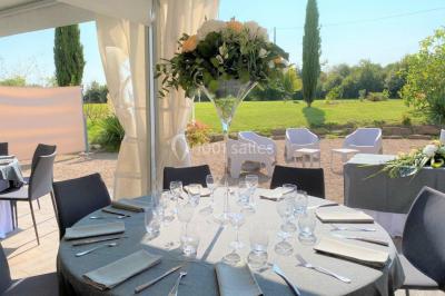 Salle de réception éclairée par des lumières violettes, avec tables hautes décorées de bougies et un espace central dégagé.