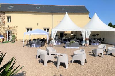 Salle de réception éclairée par des lumières violettes, avec tables hautes décorées de bougies et un espace central dégagé.