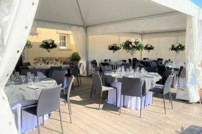 Salle de réception éclairée par des lumières violettes, avec tables hautes décorées de bougies et un espace central dégagé.