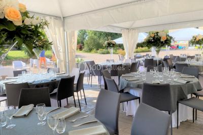 Salle de réception éclairée par des lumières violettes, avec tables hautes décorées de bougies et un espace central dégagé.