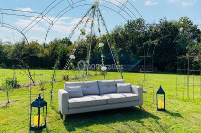 Salle de réception éclairée par des lumières violettes, avec tables hautes décorées de bougies et un espace central dégagé.