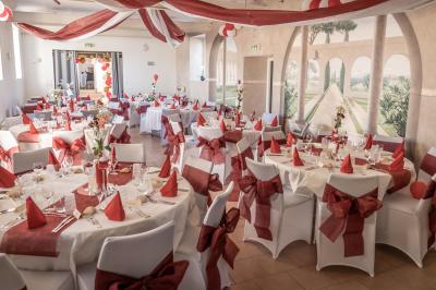 Salle de réception éclairée par des lumières violettes, avec tables hautes décorées de bougies et un espace central dégagé.