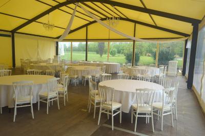 Salle de réception éclairée par des lumières violettes, avec tables hautes décorées de bougies et un espace central dégagé.
