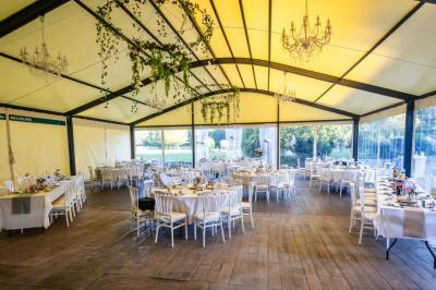 Salle de réception éclairée par des lumières violettes, avec tables hautes décorées de bougies et un espace central dégagé.