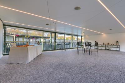 Espace intérieur lumineux avec baies vitrées donnant sur un quai, aménagé avec des fauteuils et une table basse.