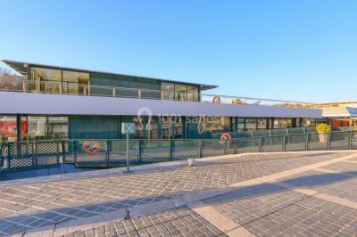 Espace intérieur lumineux avec baies vitrées donnant sur un quai, aménagé avec des fauteuils et une table basse.