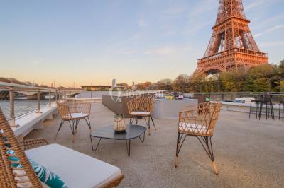 Espace intérieur lumineux avec baies vitrées donnant sur un quai, aménagé avec des fauteuils et une table basse.