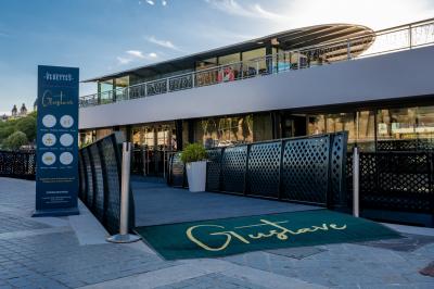 Espace intérieur lumineux avec baies vitrées donnant sur un quai, aménagé avec des fauteuils et une table basse.