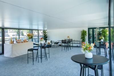 Espace intérieur lumineux avec baies vitrées donnant sur un quai, aménagé avec des fauteuils et une table basse.