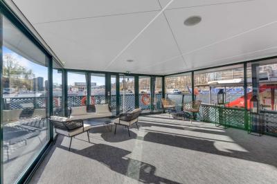 Espace intérieur lumineux avec baies vitrées donnant sur un quai, aménagé avec des fauteuils et une table basse.