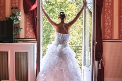Chambre élégante avec murs bleus, lit double, cheminée, miroir doré, armoire en bois et tapis géométrique.