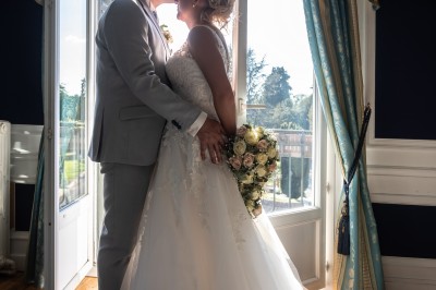 Chambre élégante avec murs bleus, lit double, cheminée, miroir doré, armoire en bois et tapis géométrique.