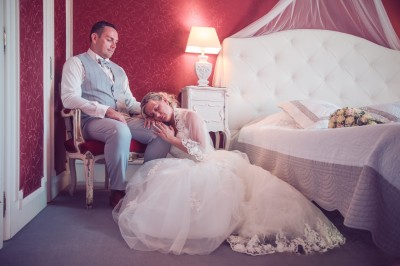 Chambre élégante avec murs bleus, lit double, cheminée, miroir doré, armoire en bois et tapis géométrique.