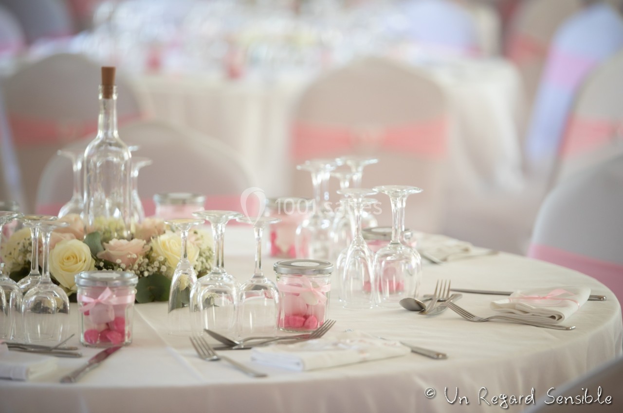 Table décorée pour un mariage avec nappes blanches, fleurs pastel, bougies et verres élégamment disposés.