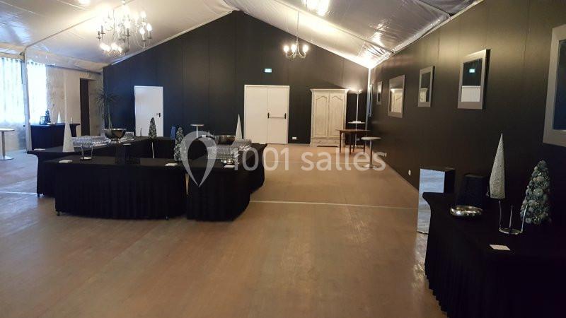 Salle de réception avec tables drapées de noir, décorations minimalistes et éclairage suspendu.