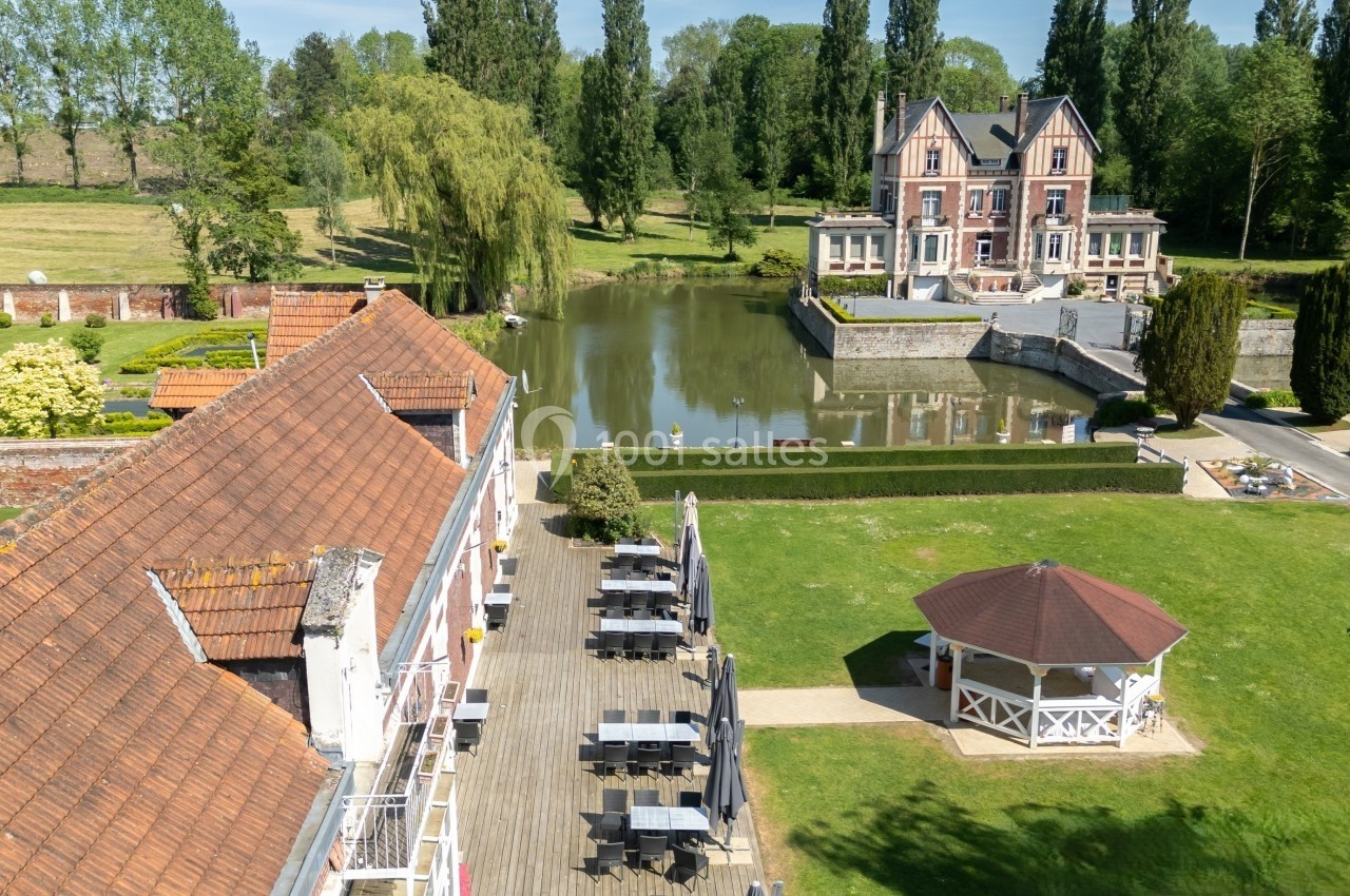 Vue aérienne d'un domaine avec un bâtiment principal au bord d'un étang, une terrasse et un kiosque dans un jardin.