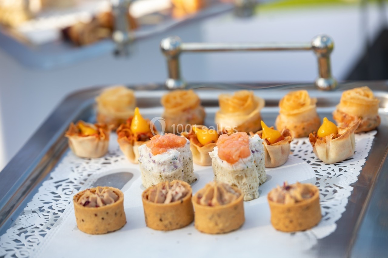 Plateau de petits amuse-bouches variés, présentés sur une nappe en dentelle blanche.