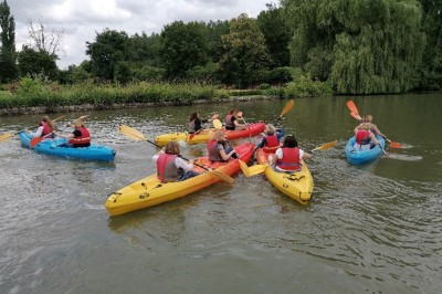Miniature Location salle Quesmy (Oise) - Château de Quesmy #39 Des personnes pagayant en kayak sur une rivière entourée de végétation sous un ciel nuageux.