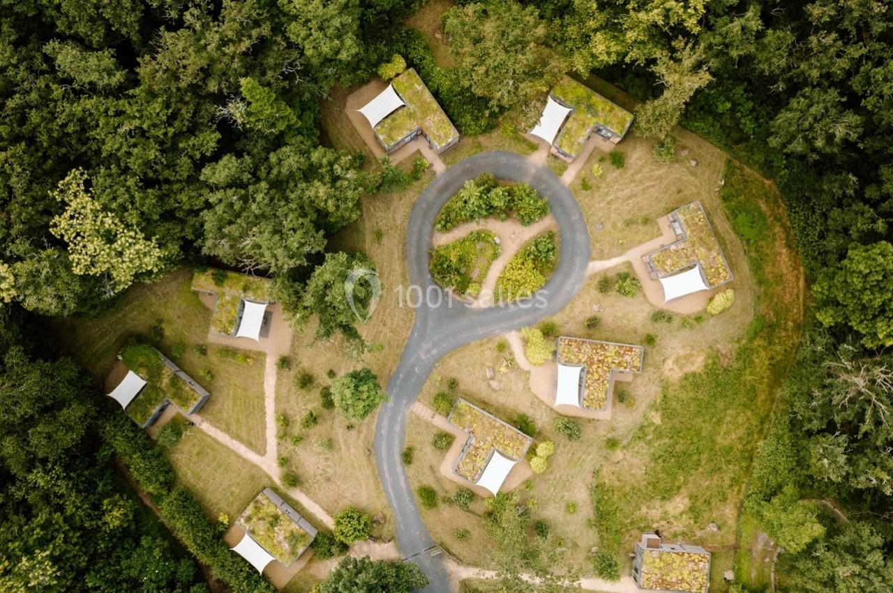 Vue aérienne d'un ensemble de petites maisons entourées de végétation et reliées par des chemins sinueux.