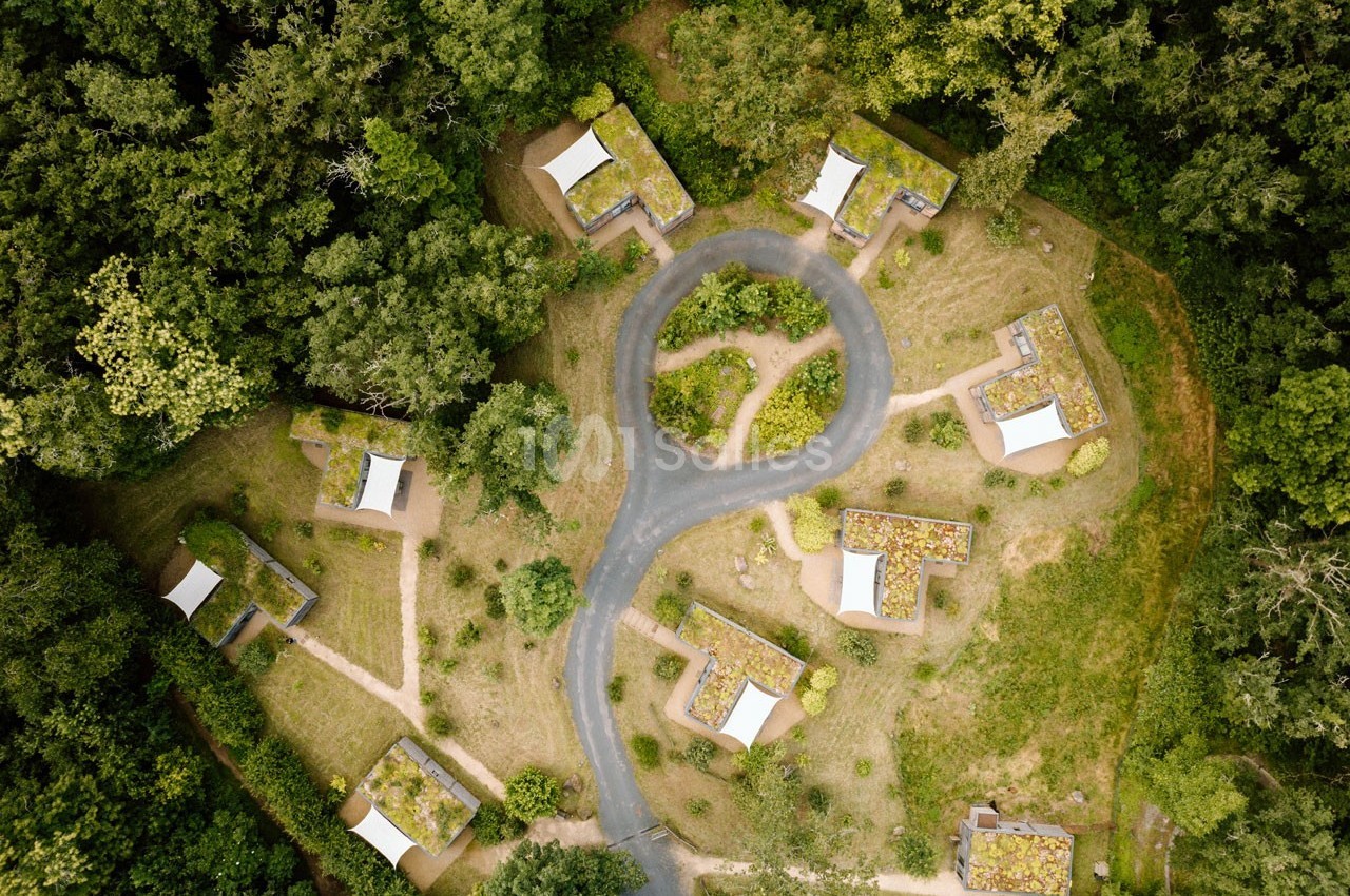 Vue aérienne d'un ensemble de petites maisons entourées de végétation et reliées par des chemins sinueux.