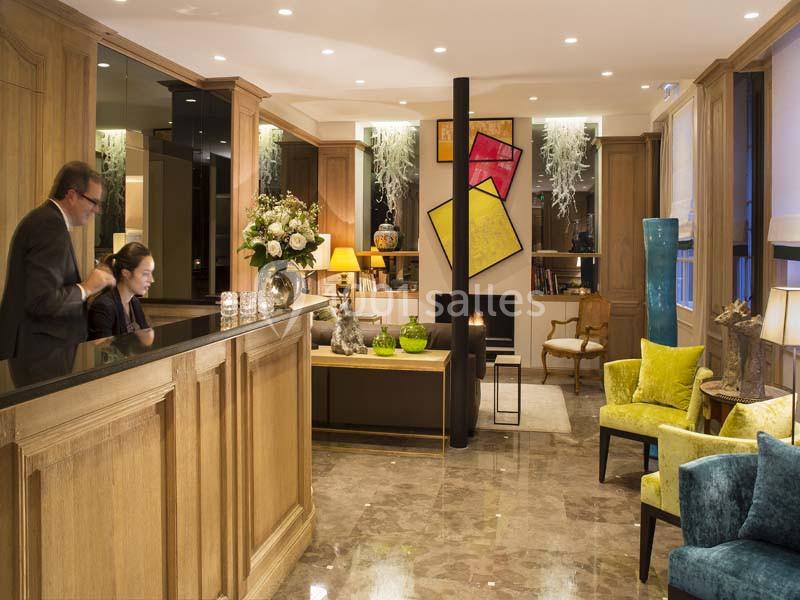 Réception d’un hôtel avec comptoir en bois, fauteuils colorés, éclairage chaleureux et décoration moderne.