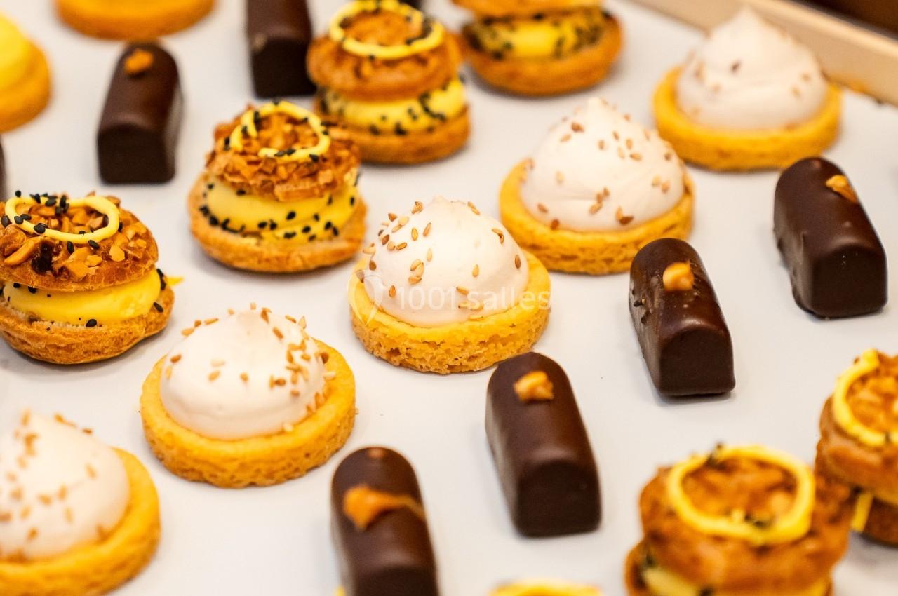 Plateau de pâtisseries variées comprenant éclairs au chocolat, tartelettes et choux garnis, disposés sur une surface blanche.