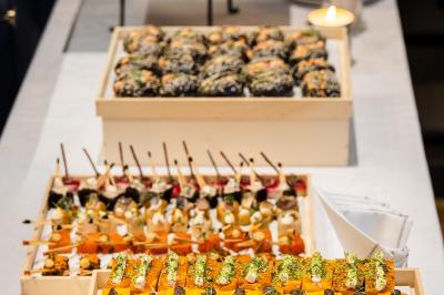 Plateau de canapés variés avec légumes, herbes fraîches et brochettes, disposés sur une table blanche.