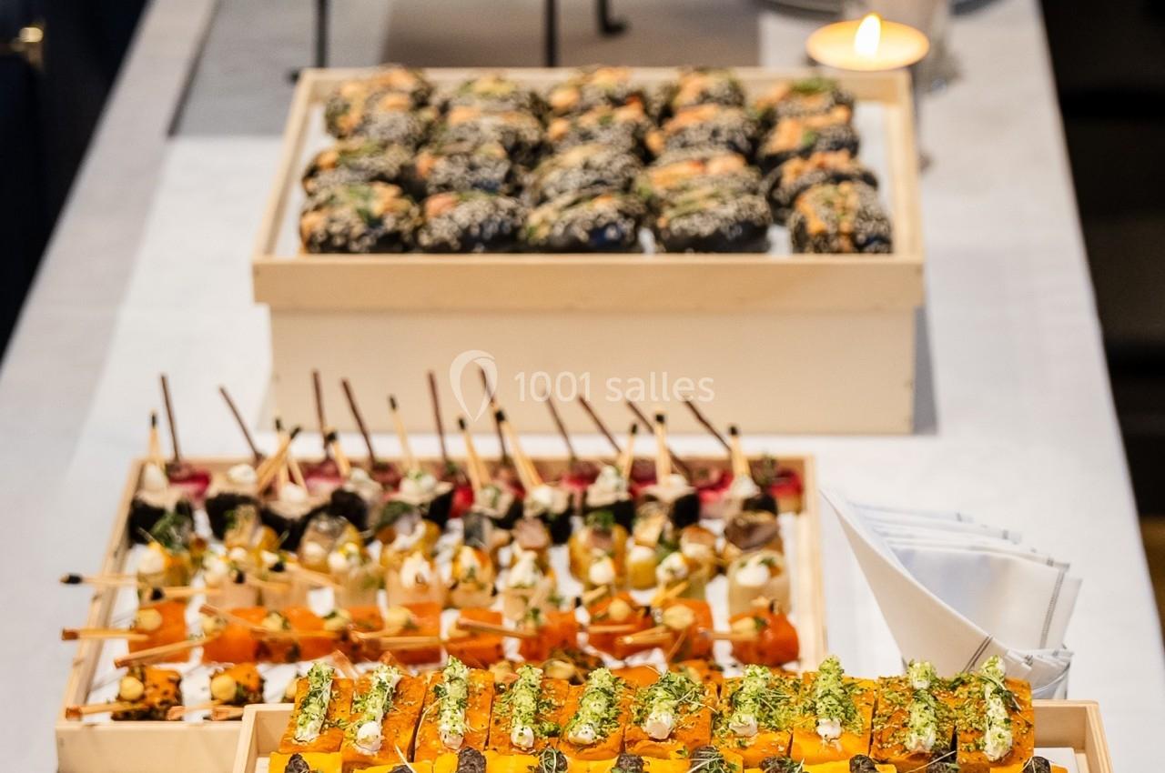 Plateau de canapés variés avec légumes, herbes fraîches et brochettes, disposés sur une table blanche.